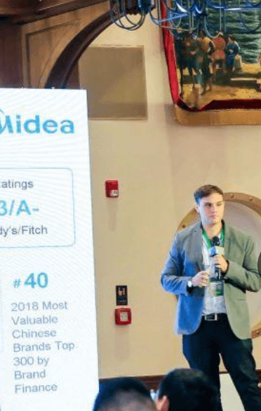 Alex Amiri presenting on stage at a Midea Group conference
